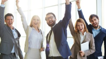 Group of ecstatic business partners looking at camera with raised arms