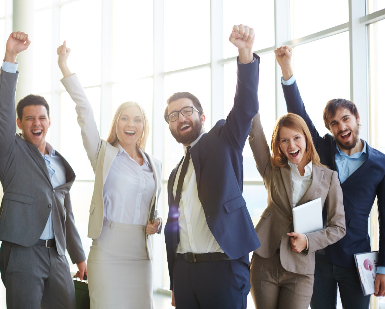 Group of ecstatic business partners looking at camera with raised arms